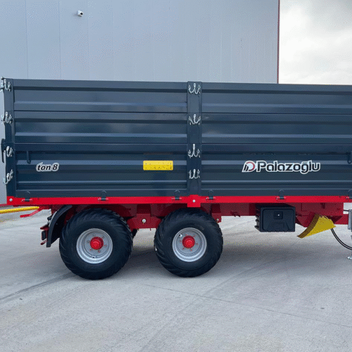 Blue Palazoglu ton8 trailer with red chassis and dual axles parked outside a gray industrial building.